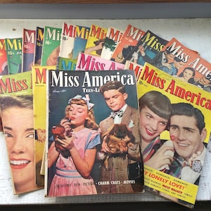 May include: A collection of vintage "Miss America" magazines. The covers feature illustrations of young people, with text including "Teen-Li", "Fashions", and "Romance". The magazines are in various colors, including yellow, pink, and green.