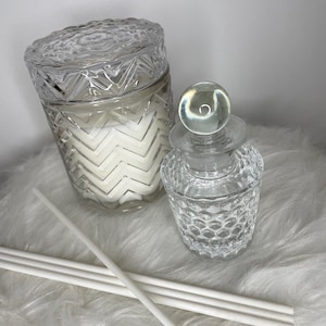 Könnte beinhalten: Ein Set aus klaren Glasdiffuserflaschen mit einem dekorativen Muster. Die Flaschen sind mit einer klaren Flüssigkeit gefüllt und haben einen Satz weißer Diffusorsticks.