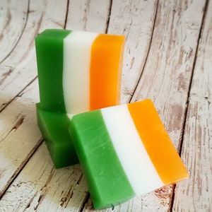 May include: Three bars of soap with green, white and orange stripes. The soap bars are stacked on top of each other.