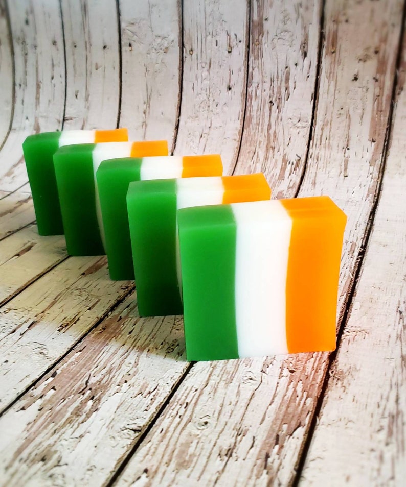 May include: Five bars of soap arranged in a row. The bars are layered in green, white, and orange, resembling the Irish flag.