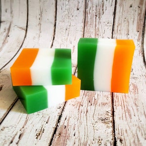 May include: Three bars of soap with green, white and orange stripes. The soap bars are stacked on top of each other.