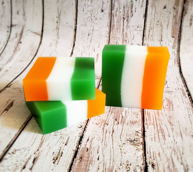 May include: Three bars of soap with green, white and orange stripes. The soap bars are stacked on top of each other.