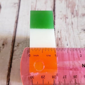 May include: A green, white and orange layered soap bar measuring 1/16 of an inch in length.