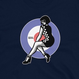 Puede incluir: Una camiseta azul marino con un gráfico de una mujer con un vestido a cuadros y gafas de sol sentada en un blanco, rojo y azul.
