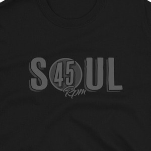 Puede incluir: Camiseta negra de manga corta con un gráfico gris de la palabra "SOUL" con un círculo que contiene el número "45" y el texto "RPM" debajo.