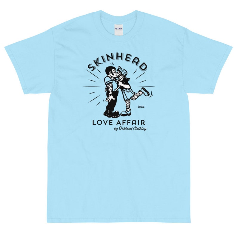 May include: A light blue t-shirt with a black and white illustration of a couple kissing. The illustration is surrounded by a circle with the text "SKINHEAD LOVE AFFAIR by Orblood Clothing".