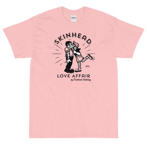 May include: A pink t-shirt with a black and white illustration of a couple kissing. The illustration is surrounded by a circle with the text "SKINHEAD LOVE AFFAIR by Orblood Clothing".