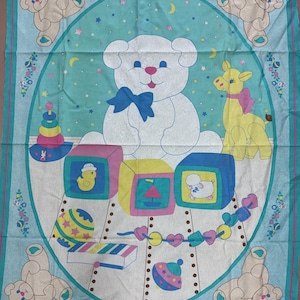 May include: A rectangular fabric panel featuring a central oval design on a light blue background. The print displays a large white teddy bear with a blue bow, surrounded by colorful toy blocks, a yellow giraffe, a ball, and a xylophone.