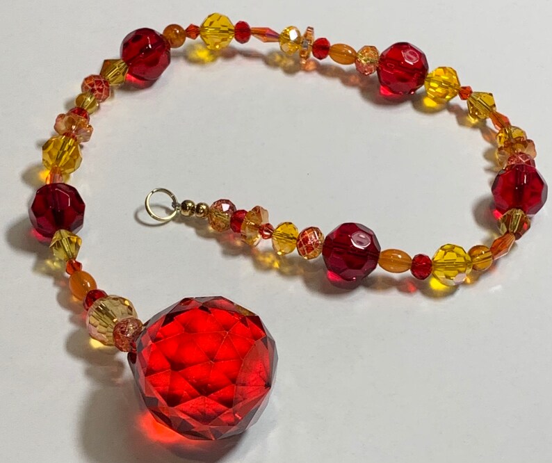 Suncatcher with red drop focal crystal yellows Hand strung reds oranges
