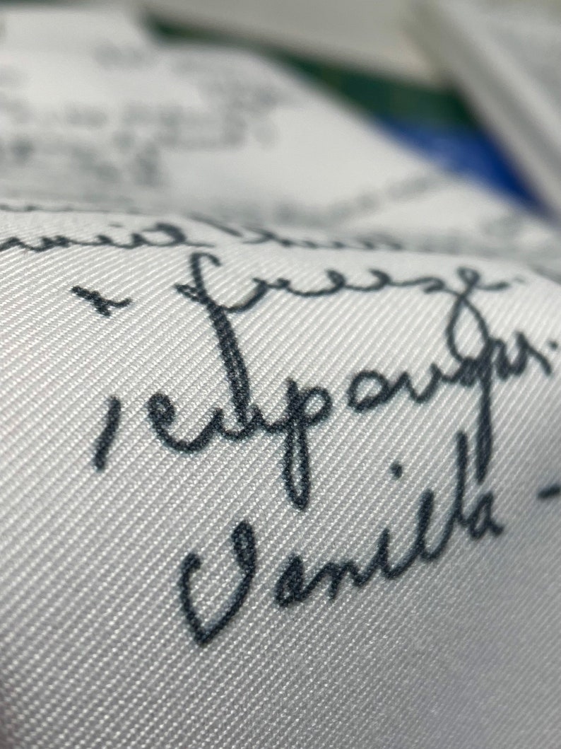 May include: White fabric with black handwritten text that reads "I'm free, I'm happy, I'm vanilla!"