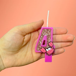 May include: Pink glitter number four birthday candle with a pink and white crab on the front.