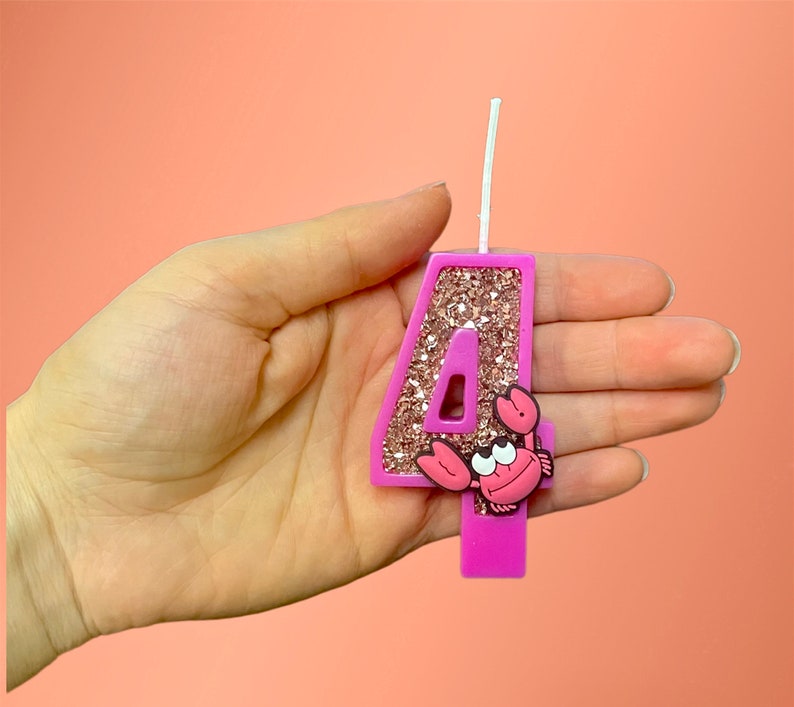 May include: Pink glitter number four birthday candle with a pink and white crab on the front.