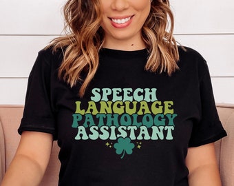 May include: Black t-shirt with the text "SPEECH LANGUAGE PATHOLOGY ASSISTANT" in a retro font with green, yellow, and blue colors. A shamrock with glitter is below the text.
