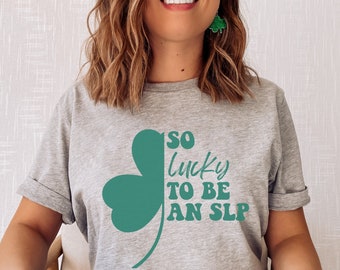 May include: A gray t-shirt with a green shamrock design and the text "So lucky to be an SLP".