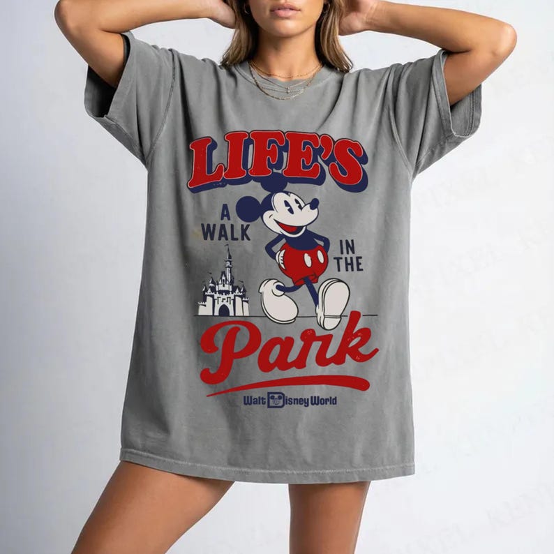 Puede incluir: Camiseta gris con Mickey Mouse y el texto "Life's a Walk in the Park" en rojo y azul. El dise&ntilde;o incluye un castillo y "Walt Disney World" en rojo.