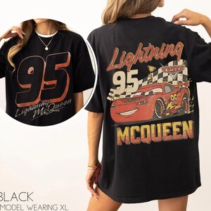 May include: Black t-shirt featuring the number 95 and the words "Lightning McQueen" in a distressed font on the front. The back of the shirt displays a graphic of Lightning McQueen with the number 95 and the word "McQueen".