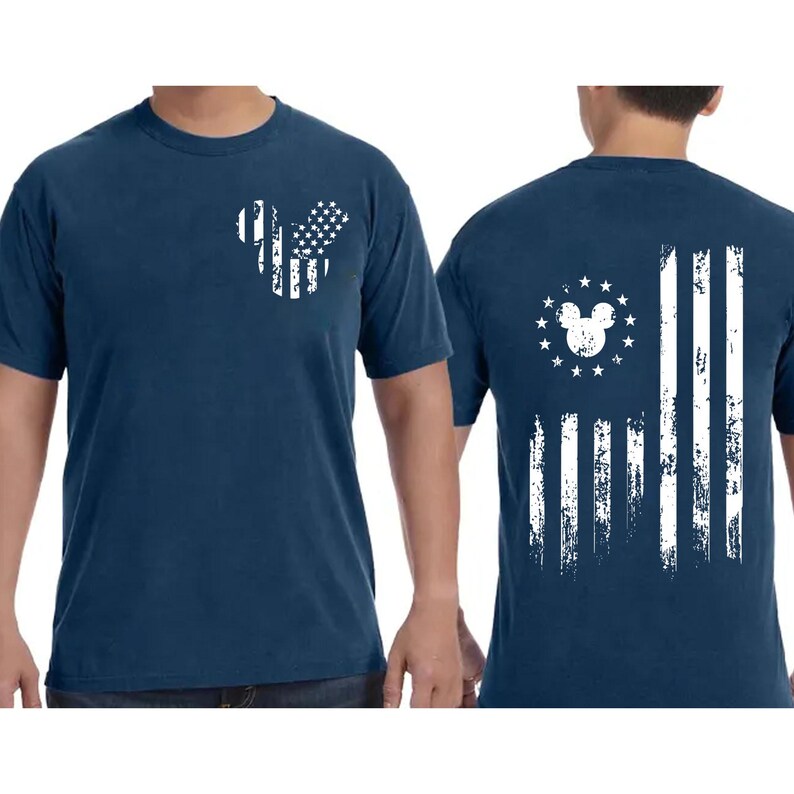 May include: Navy blue t-shirt featuring a distressed white graphic of the American flag in the shape of a mouse head on the front. The back of the shirt displays a similar design with the flag stripes and a mouse head surrounded by stars.