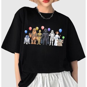 May include: Black t-shirt with a graphic of Star Wars characters holding balloons. The characters include R2-D2, Chewbacca, C-3PO, Darth Vader, a Stormtrooper, Princess Leia, and Grogu.