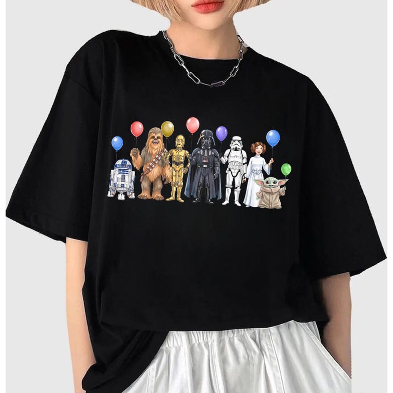 May include: Black t-shirt with a graphic of Star Wars characters holding balloons. The characters include R2-D2, Chewbacca, C-3PO, Darth Vader, a Stormtrooper, Princess Leia, and Grogu.