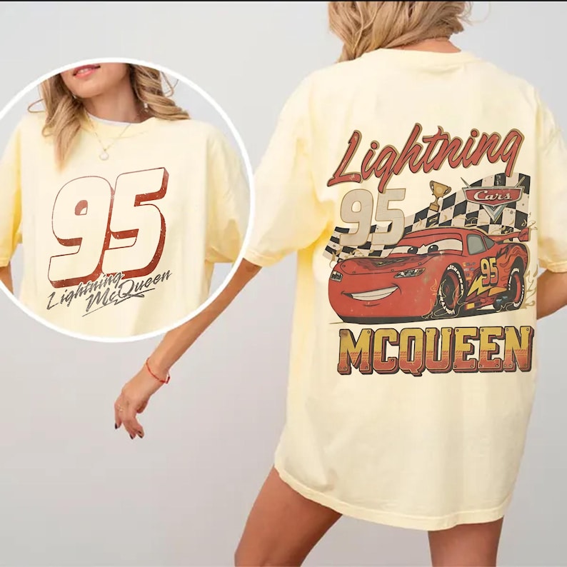 May include: A light yellow t-shirt featuring the number 95 and the words "Lightning McQueen" in a red and white design on the front. The back of the shirt displays a graphic of Lightning McQueen with the words "Lightning McQueen" and "Cars".