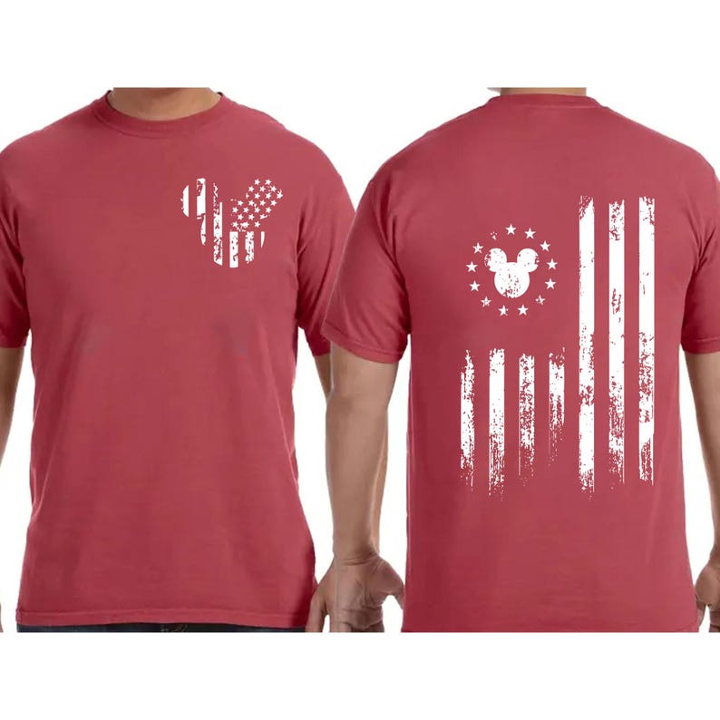 May include: Red t-shirt with a distressed white American flag design. The front features a Mickey Mouse head shape with stars and stripes. The back displays a larger flag design with a Mickey Mouse head and stars.