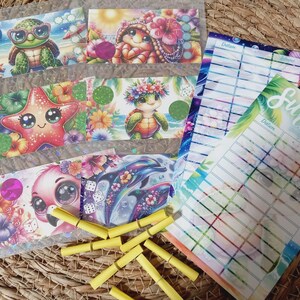 Könnte beinhalten: Eine Sammlung farbenfroher, illustrierter Karten mit Cartoon-Meeresbewohnern wie Schildkröten, Seesternen und Flamingos. Die Karten sind mit gelben Wäscheklammern und zwei Papierbögen mit dem Text "Summer Cuties" und linierten Abschnitten angeordnet.