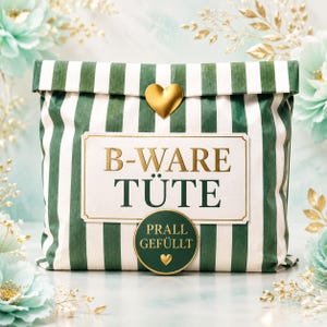 Könnte beinhalten: Eine rechteckige Papiertüte mit vertikalen dunkelgrünen und weißen Streifen. Die Tüte hat einen goldenen herzförmigen Verschluss oben, ein weißes Etikett mit der Aufschrift B-WARE TÜTE in Gold sowie einen runden grünen Aufkleber mit PRALL GEFÜLLT.