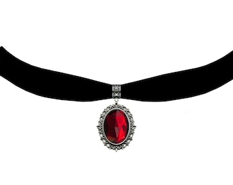 May include: A black velvet choker necklace with a silver pendant featuring a large red oval-shaped gemstone.