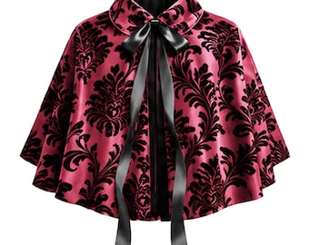 May include: A short cape featuring a deep magenta satin base with a black velvet damask pattern. The garment has a rounded collar and a long black satin ribbon tie at the center front. The hem is flared and the interior is lined in black fabric.