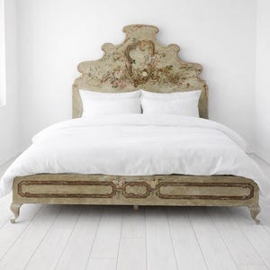 May include: A vintage-style bed with a floral headboard and footboard. The headboard and footboard are painted in a light green colour with floral accents. The bed is covered with a white duvet and pillows. The bed frame is approximately 200 cm long.
