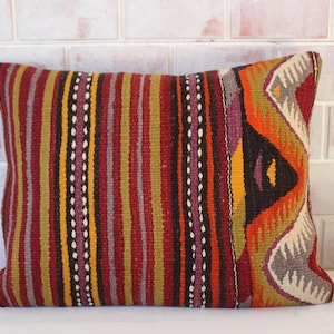 May include: A colorful striped and patterned throw pillow with a geometric design in shades of red, orange, yellow, brown, purple, and gray.