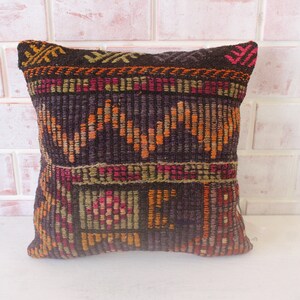 May include: A dark brown throw pillow with a colorful geometric pattern. The pattern features shades of orange, red, green, and pink.