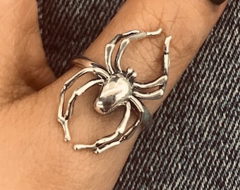 Peut inclure: Une bague araignée argentée avec des détails complexes. La bague est portée sur un doigt, mettant en valeur le design arachnide. Les pattes de la bague s'étendent autour du doigt, créant un accessoire unique et accrocheur.