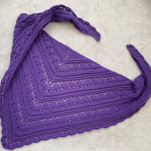 Puede incluir: Un chal de ganchillo morado con un diseño de encaje. El chal está doblado por la mitad y tiene un borde de flecos.