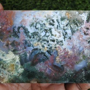 May include: A rectangular polished slab of moss agate featuring a complex pattern of translucent white, deep forest green, earthy brown, and soft pink inclusions. The stone displays a smooth, flat surface with natural mineral dendrites.