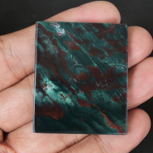 May include: A square piece of green and red jasper with a swirling pattern. The stone is polished and has a smooth surface.