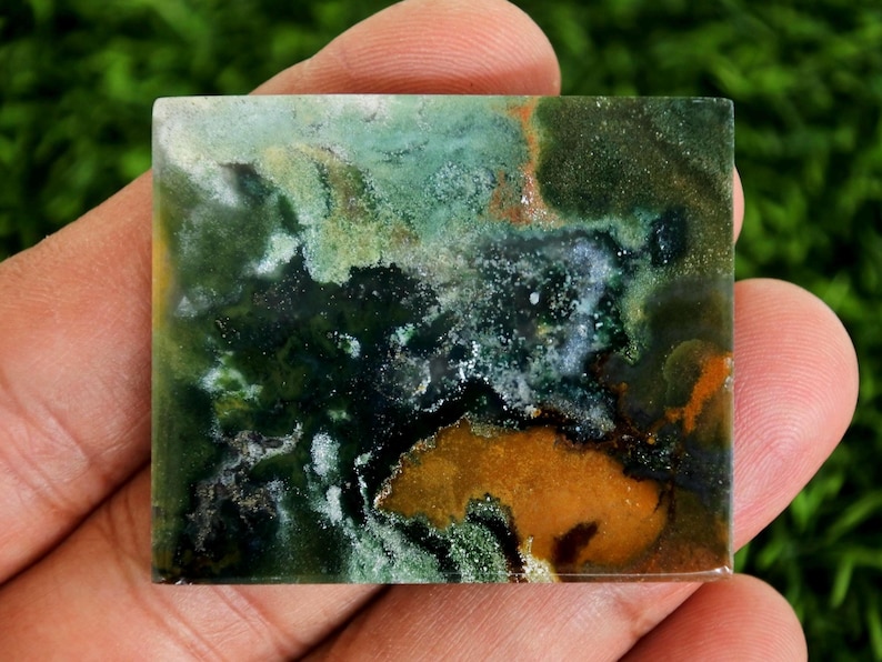 Peut inclure: Une pierre carr&eacute;e aux motifs uniques de vert, blanc et orange. La surface pr&eacute;sente un aspect marbr&eacute;, avec un m&eacute;lange de nuances sombres et claires. L'ensemble d&eacute;gage une esth&eacute;tique naturelle et terreuse, adapt&eacute;e &agrave; la bijouterie ou &agrave; la d&eacute;coration. Mesures en centim&egrave;tres.