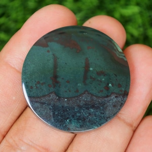 May include: A round, green and brown agate cabochon with a polished surface. The stone has a layered pattern with dark brown and black accents.