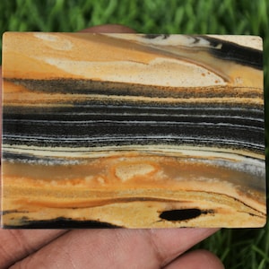May include: A close-up of a banded agate slab with a layered pattern of black, white, and brown. The agate has a smooth, polished surface.