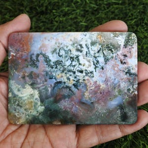 May include: A rectangular slab of polished moss agate featuring a complex pattern of translucent white, deep forest green, and earthy reddish-brown inclusions. The stone displays a smooth, flat surface with natural mineral formations.