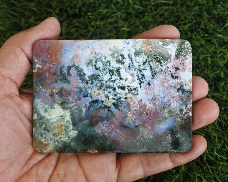 May include: A rectangular slab of polished moss agate featuring a complex pattern of translucent white, deep forest green, and earthy reddish-brown inclusions. The stone displays a smooth, flat surface with natural mineral formations.