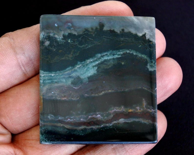 以下が含まれることがあります： 暗い緑、ティール、茶色の色合いの層状パターンを持つ、正方形で研磨された石。 石は光沢のある仕上げで、天然の鉱物標本のようです。 色が混ざり合い、ユニークな抽象的なデザインを作り出しています。