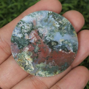 May include: A round, polished, green, white, and red agate stone with a swirling pattern.