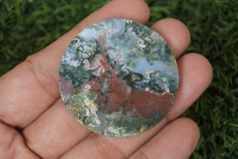 May include: A round, polished, green, white, and red agate stone with a swirling pattern.