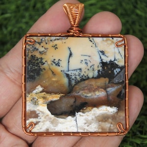 May include: A copper wire wrapped pendant featuring a square piece of agate with brown, white, and black patterns.
