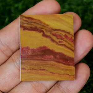 May include: A square piece of polished stone with a yellow, orange, and red banded pattern.