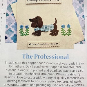 May include: A handmade card featuring a brown dachshund wearing a blue and white checked shirt. The card has a blue and white floral design and the text "Happy Father's Day!" and "Lots of woofs from Wilbur".
