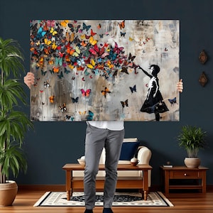 May include: A large rectangular canvas art print featuring a girl in a black dress reaching towards a swarm of colorful butterflies. The butterflies are in shades of red, orange, yellow, blue, and purple against a neutral background.