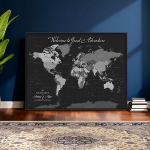 May include: A framed world map in shades of gray and black, with country borders and names. The text "Welcome to Great Adventure" is at the top, and "The Adventures of Arthur & Alice" is at the bottom. The map is displayed on a dark wall.