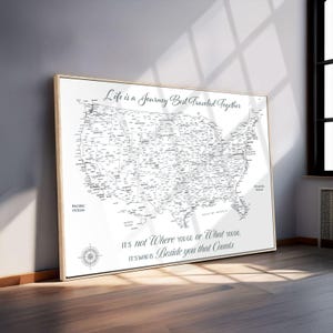 May include: A framed map of the United States, rendered in black and white, with state and city names. The map is surrounded by a light wooden frame. The text "Life is a Journey Best Traveled Together" is at the top, and other text is at the bottom.